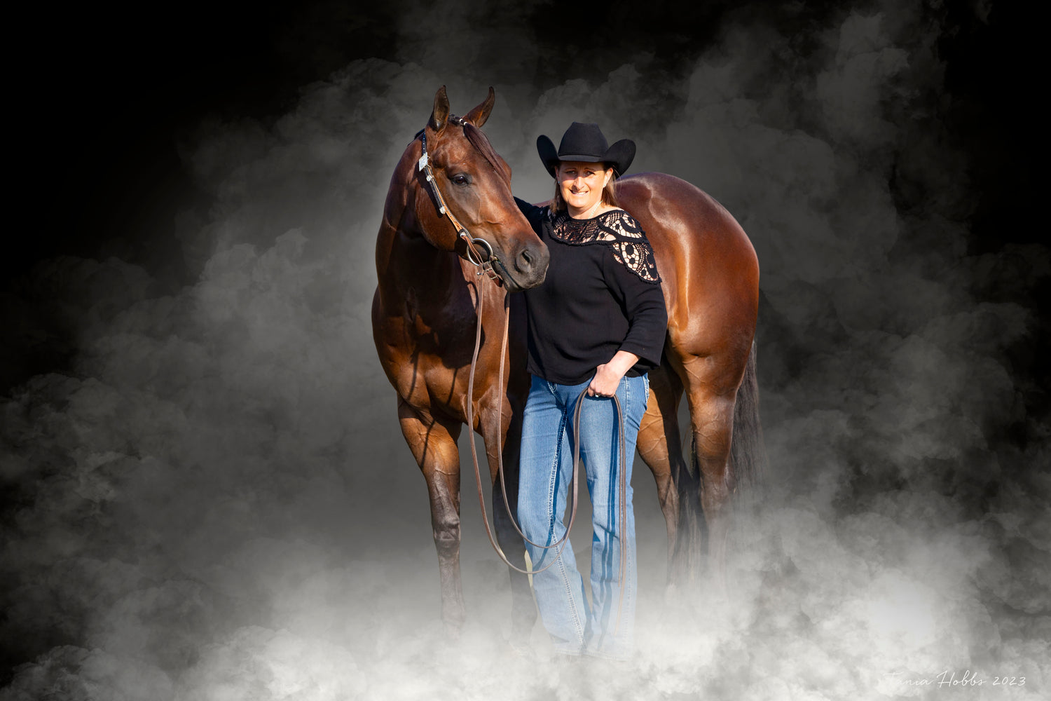 Owner/founder Mel with her paint horse SId with black background and a fog effect